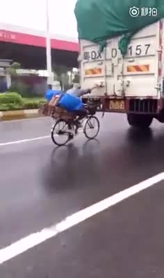 Xe đạp bám đuôi ôtô tải tránh mưa