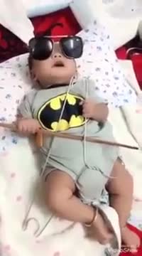 Bé trai ba tháng tuổi kéo đàn bằng đũa và mắc áo