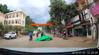 Xe máy đang chạy bị bạt bay từ nóc xe tải trùm gọn trên đường